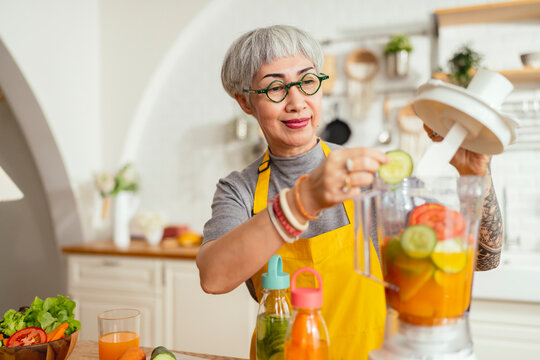 healthy asian aunt retired female woman enjoy making cook clean food breakfast for her healthy food lifestyle,smiling cheerful woman silver hair with tattoo prepare smoothie juice drink for her health