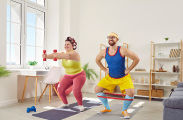Fototapeta na wymiar Overweight happy fat woman with funny bearded man in bright sportswear doing fit exercises on mat with stretching band and dumbbells at home together. Concept of couple family sport and fitness.