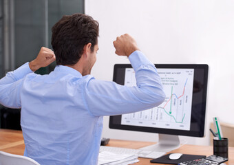 Fototapeta premium Great success. Rearview shot of an excited-looking businessman sitting at his desk.
