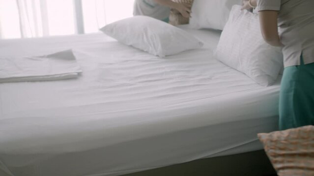 Womans changing the bedding in the room. Employees, two maids of the hotel, professionally make the bed in the client's room. Five-star hotel concept and quality room service. 4K.