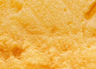 The surface, the fibers of the sponge. Golden yellow cleaning sponge, porous surface, air bubbles.