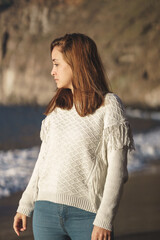 Caucasian woman with brown hair and white shirt on the beach at sunset.