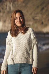 Caucasian woman with brown hair and white shirt on the beach at sunset.
