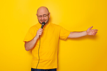 Man holding microphone and singing on yellow color background