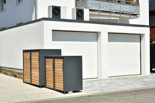 Luftw&auml;rmepumpe, Klimaanlage f&uuml;r Heizung und Warmwasser aufgebaut auf der Doppelgarage eines neu gebauten Wohnhaus sowie Ger&auml;teboxen vor der Garage