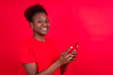 Young african american woman isolated on a red background smiling with the mobile phone, study session