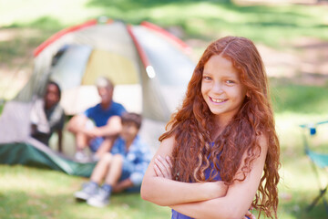 Its time to have some fun. a young girl standing in front of her campsite.