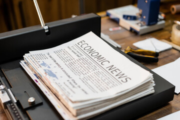printed newspapers with economic news inside of professional paper trimmer machine.
