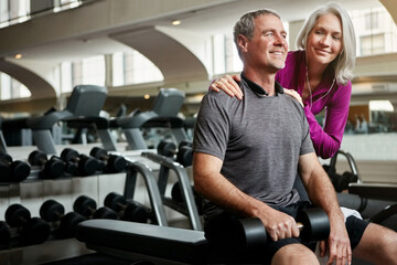 We always happy after a great workout. a senior married couple smiling and taking a break from their workout at the gym.