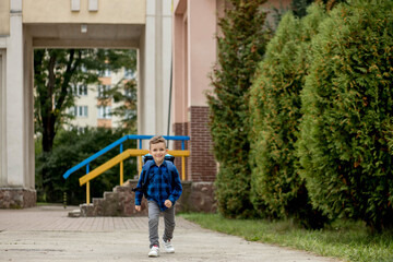 Fototapeta na wymiar Little first grader with backpack goes home from school