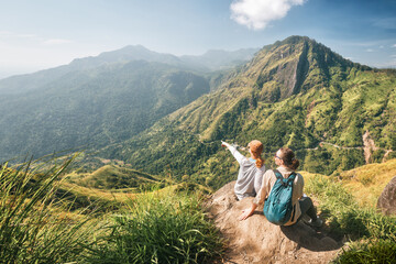 Two traveler friends share emotions on background of mountain peak "Adam's Peak", Sri Lanka.