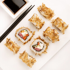 Sushi plate on white background, rolls set with tuna flakes on white background from above. Top view of traditional japanese cuisine. Asian food with chopsticks design.