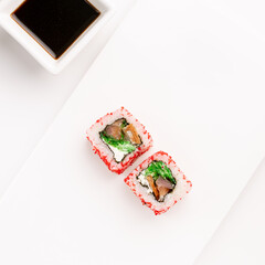 Sushi plate on white background, rolls set with red tobiko egg on white background from above. Top view of traditional japanese cuisine. Asian food with chopsticks design.