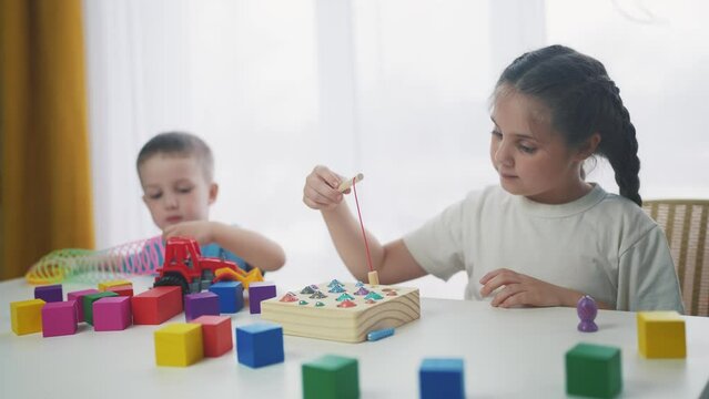children at the table in kindergarten play an educational game fishing. development of fine motor skills in children. children play educational game catch fish in kindergarten dream. game kid concept