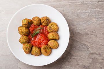 Atlantic salmon meatballs with spinach served with tomato sauce on a white plate on stone table....