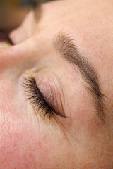 Obraz premium Close-up of closed eye of female model. Permanent make-up of the eyelids, eyelash tattooing.