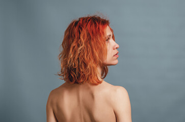 Portrait of a with skinny shoulders, standing with her back to the camera with red hair