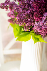 Bouquet of spring lilac flowers in a white vase in a light interior. Nice light interior photo.