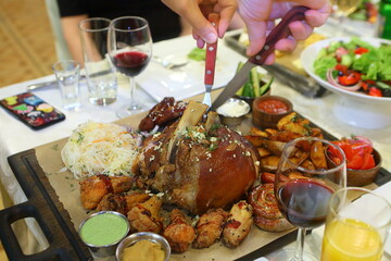 Male hands cut a pork knuckle with a knife