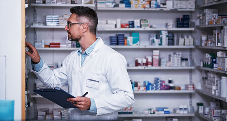 Naklejka na ściany i meble Nobody knows pharmaceutical merchandising like he does. a mature pharmacist doing inventory in a pharmacy.