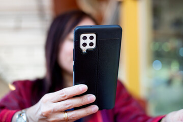 Selective soft focus on mobile phone close up, on background blurred woman using smartphone scrolling, on the phone for online shopping.
