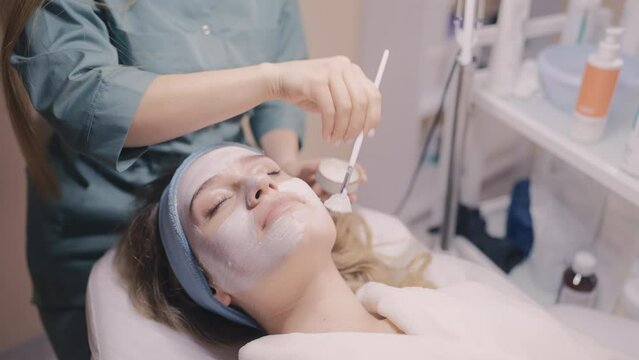 Aesthetician applying face mask to her patient, cosmetic treatments, beautician