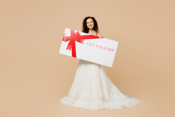 Full body happy young woman bride wear wedding dress posing hold store big gift certificate coupon...