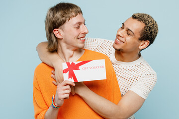 Young fun couple two gay men wearing casual clothes together hold store point on gift certificate...