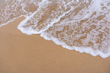 Espuma de olas en la arena amarilla