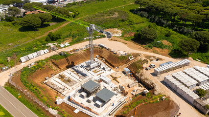 Aerial view of a green industrial tower crane operating in high building construction site. This...