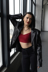 Girl in red top and leather jacket by the window