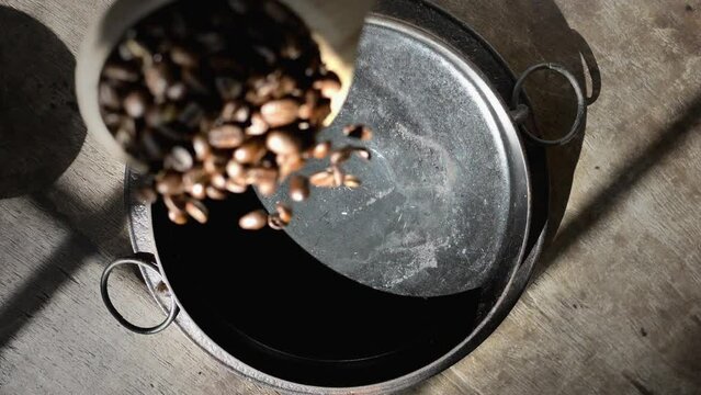 Coffee Beans poured in slow motion into roasting pan overhead view