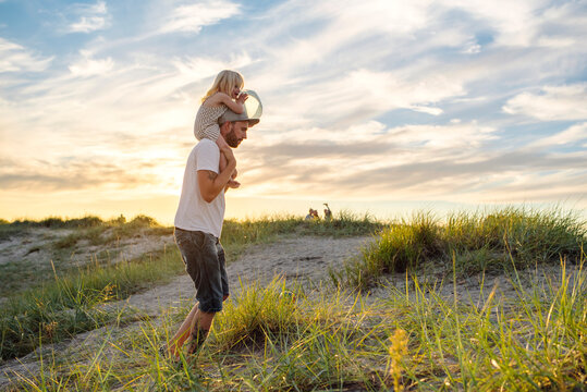 Father giving daughter (2-3) piggyback ride on grassy beach