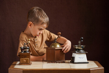 Fototapeta na wymiar Little boy and antique coffee grinders on the table.