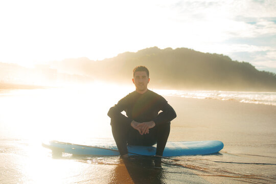 Man sitting on surfboard in beach