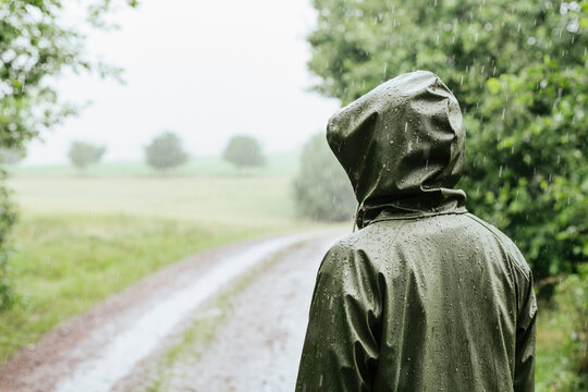 Rear view of woman in green raincoat standing in rain