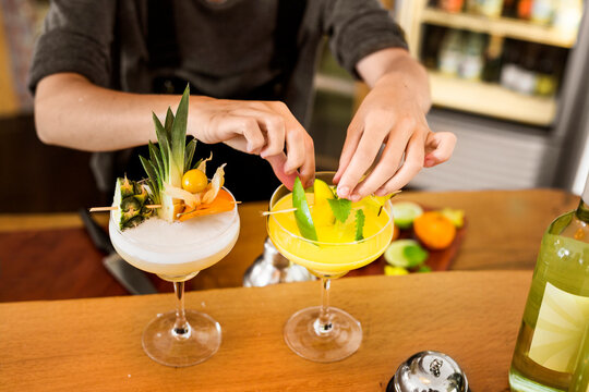 Mid section of bartender preparing colorful cocktails