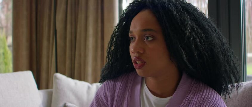 Black African-American female watching TV at home, sees something disgusting or scary