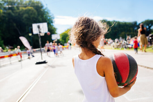 Rear view of girl (6-7) holding basketball