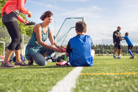 Mothers helping sons (10-11, 12-13) get dressed for soccer practice