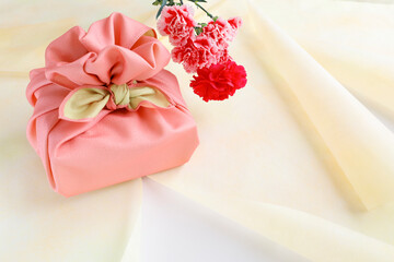 ピンクの風呂敷でラッピングしたギフトと花　贈り物のイメージ
