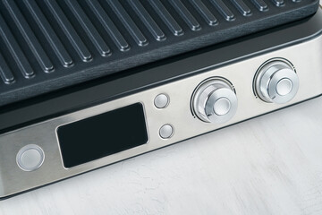 Obraz premium Electric grill. Modern kitchen portable grill tool for modern kitchen for grilling meat, vegetables and snacks for dinner or party on light gray background. Place for text or advertisement. Mock up.