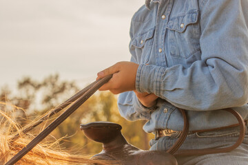 Close up of a young boys hands, while riding a horse and holding the reins tight