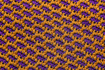 Knitted background. Seamless purple yellow crochet fabric with brick pattern.