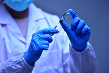 Female doctor wearing blue hand is using syringe to aspirate vaccine from vial. epidemic concept, virus, ,corona, health and medical