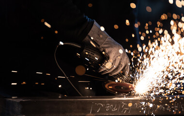 Man working on iron with grinder. Man at work. Sparkles and fire from grinder cutting. Grinder. Worker.