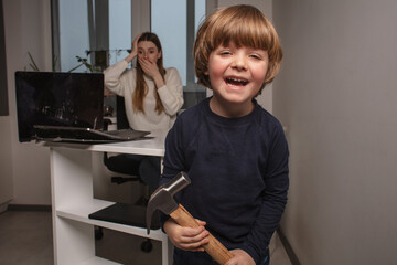 Happy child smashes mom's work laptop to spend more time together. The toddler laughs because he...