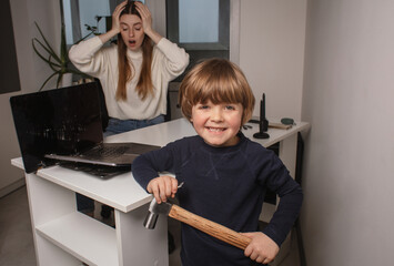 Happy child smashes mom's work laptop to spend more time together. The toddler laughs because he...