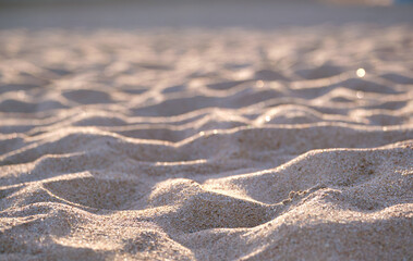 Close up of clean yellow sand surface covering seaside beach illuminated with evening light. Travel and vacations concept