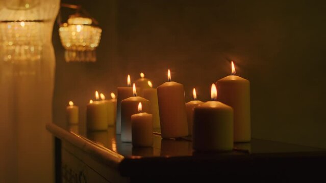 Black candles light up the dark background as a witch performs a magic ritual with voodoo and paganism. The close-up reveals the intensity of the mystic rite.